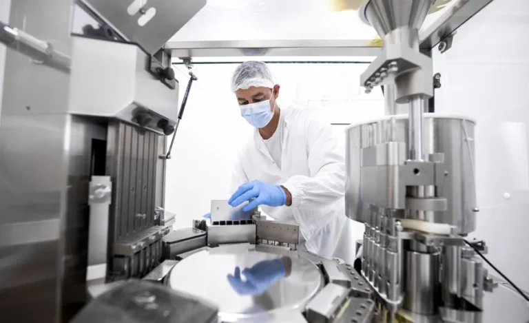 Pharmaceutical technician in a protective clothing equipment seen in a laboratory during a manufacturing process
