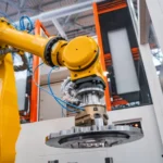 Industrial robotic arm holding metal gear component in automated