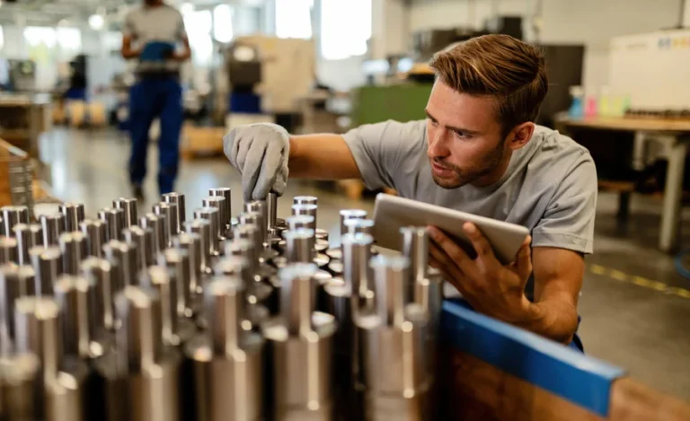 Young steel worker performing quality control of manufactured products in a warehouse.