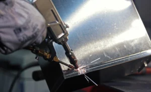 Spot welding sheet metal with precision tool. Close-up of a worker using a spot welding machine to fuse sheet metal parts with sparks flying in an industrial setting.